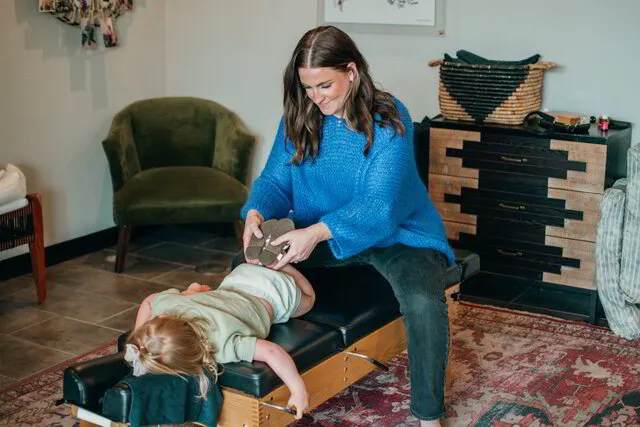 Dr. Morgan Plantamura gently adjusts a child on a chiropractic table, demonstrating her expertise and care in family wellness and pediatric chiropractic health.