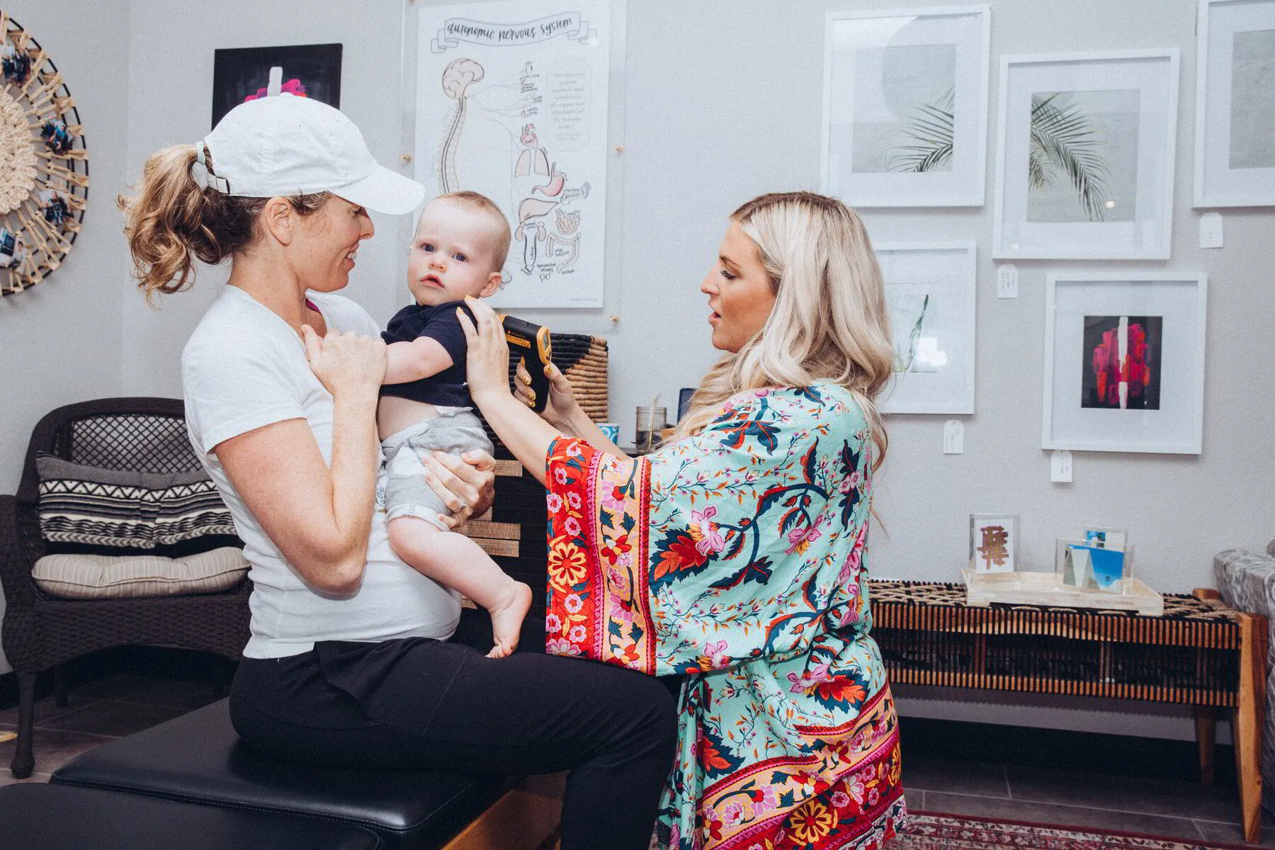 Dr. Morgan engages with a baby held by a smiling mother, reflecting a warm and comfortable chiropractic care experience