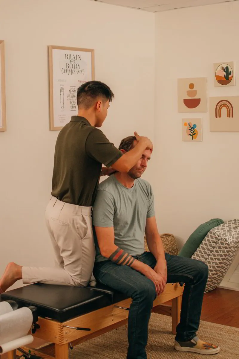 Dr. Binh applies his chiropractic expertise to a seated patient, illustrating his commitment to holistic patient care