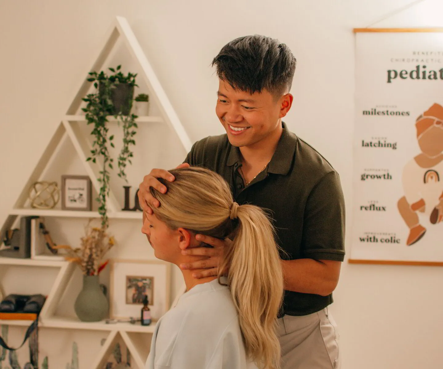 Dr. Binh smiles warmly while gently examining a patient's neck, in his clinic