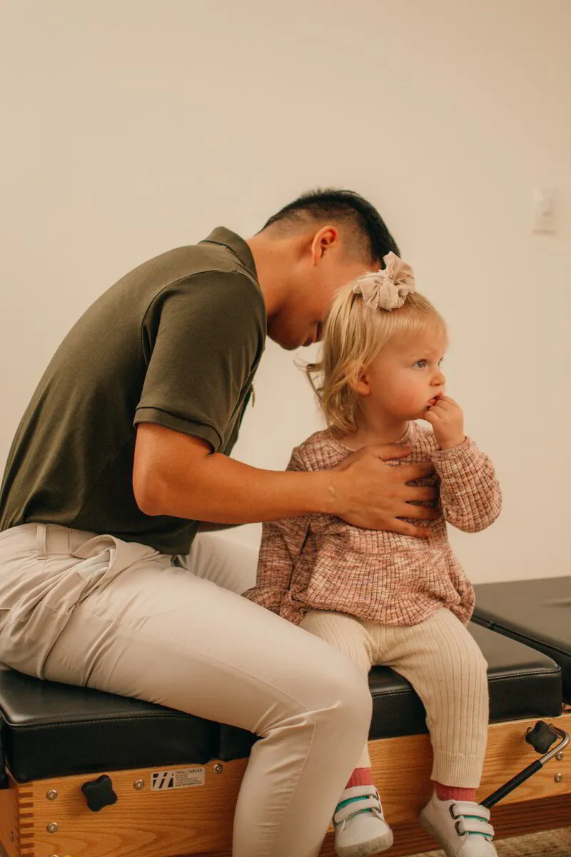 Dr. Binh compassionately examines a young child in his clinic, showcasing his expertise in pediatric chiropractic care