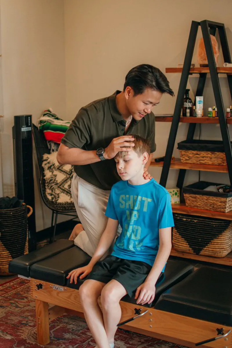 Dr. Binh attentively checks a young boy's spinal alignment