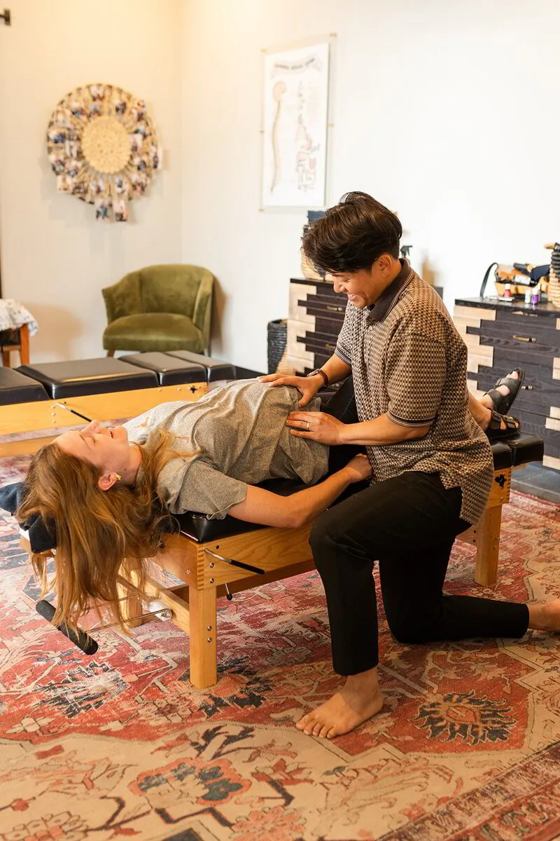 Dr. Binh gently manipulates a patient's spine, showcasing a technique to relieve discomfort as the patient relaxes on the chiropractic table