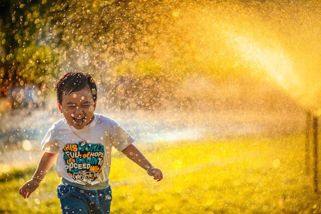 Kid playing with a sprinkler in summer