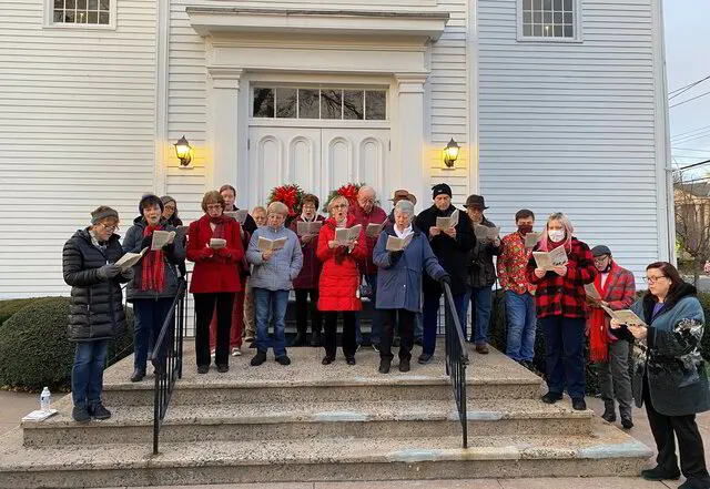 Church choir caroling on steps in winter