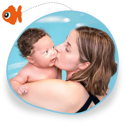 An adult in a baby swimming lesson kisses her child on the cheek