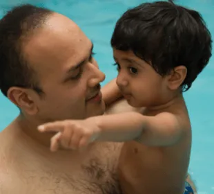 A boy and his dad are in the swimming pool as part of a swimming lesson