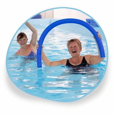 Two women smile as they take part in a fitness swimming class at Swim Works pool in Warwickshire