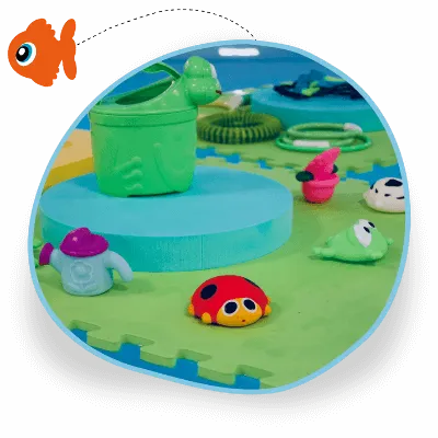 A foam board floats in a swimming pool and on top of it are lots of plastic baby sensory toys including a ladybird and a frog