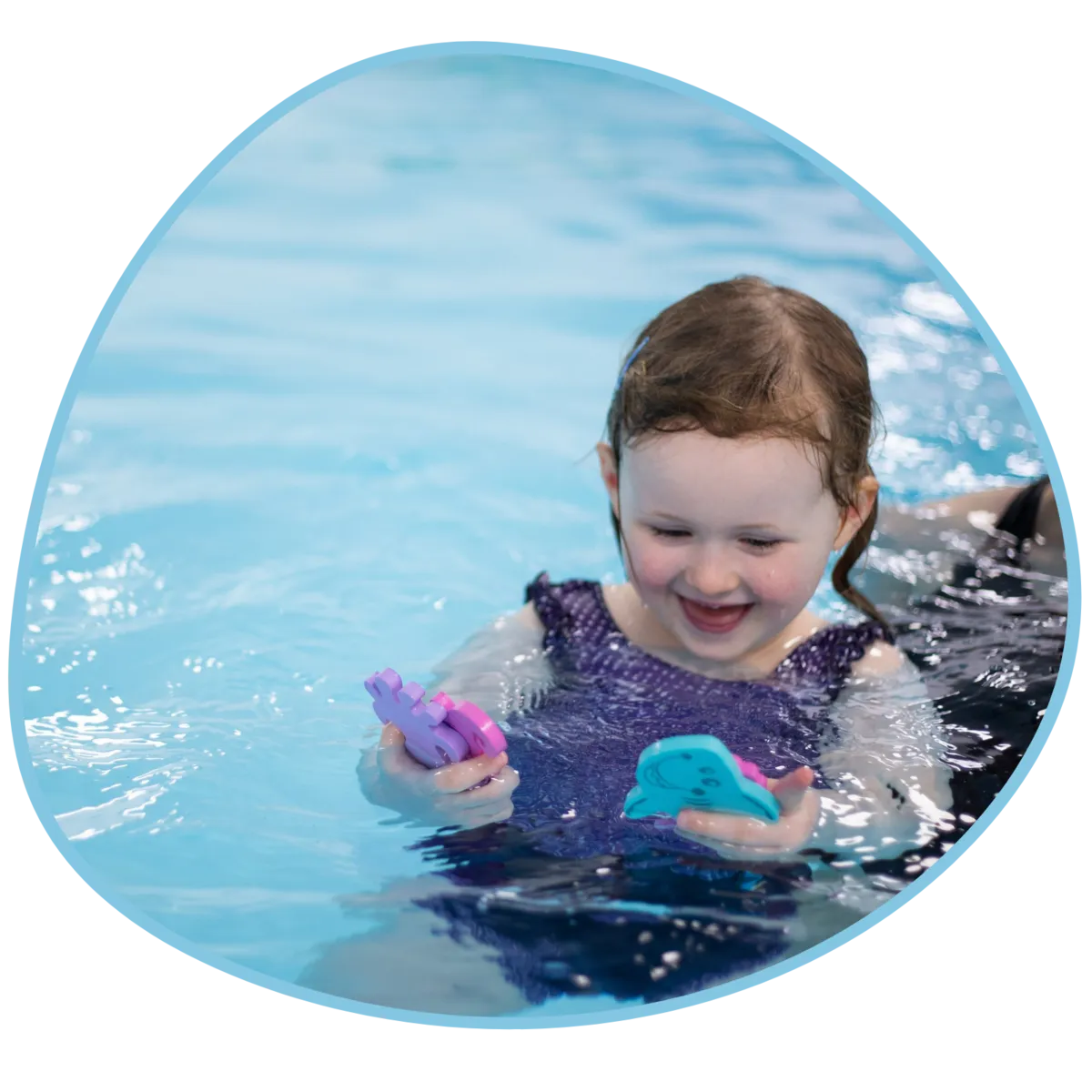 A young girl plays with toys in a swimming pool