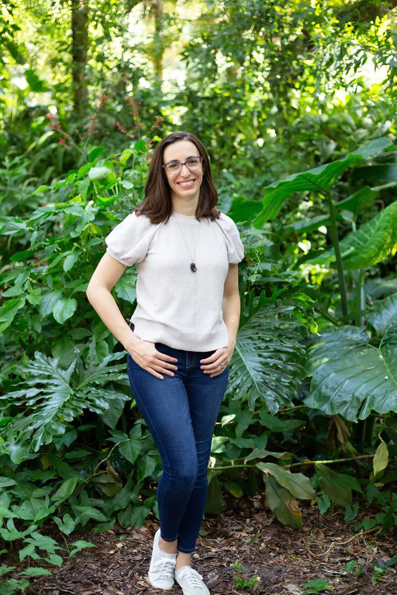 Photo of Co-Owner and Licensed Massage Therapist, Stephanie Mainit, standing in front of the foliage at Dickson Azalea Park in Orlando, Florida. 