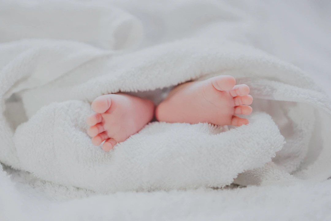 Baby's feet peeking out from a soft white blanket, symbolizing innocence and new life.