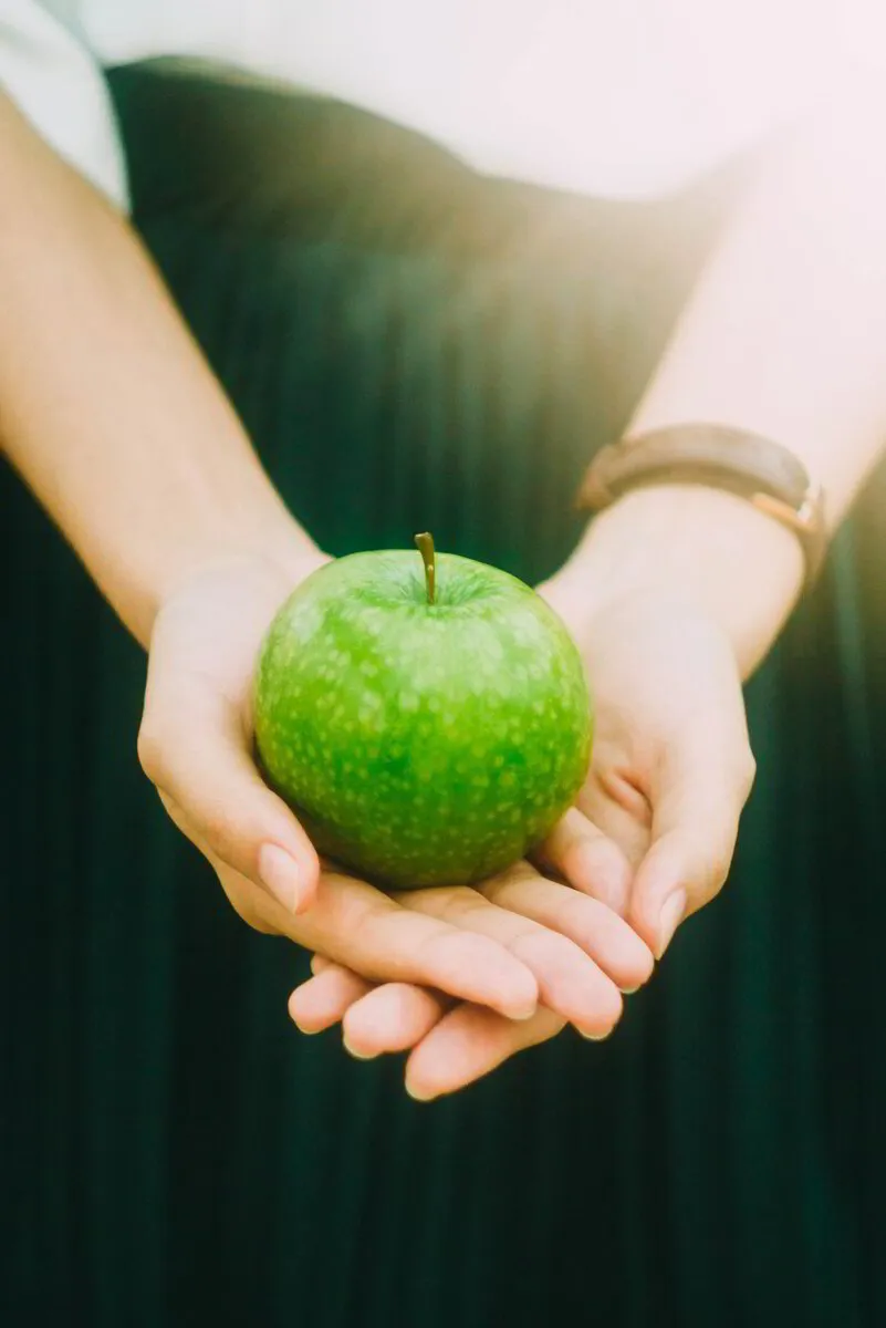 Person holding a fresh green apple in cupped hands, symbolizing healthy eating.