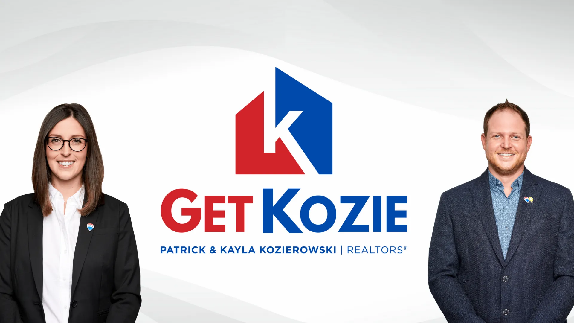 In this professional portrait, a dynamic husband and wife real estate team, Patrick and Kayla Kozierowski of ReMax Superstars, stand side by side, exuding confidence and warmth. Both are elegantly dressed in business attire, projecting a polished and approachable image. Patrick, on the left, wears a tailored suit with a ReMax lapel pin, while Kayla, on the right, dons a chic business dress, complementing their professional appearance.