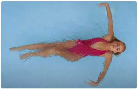 A girl gracefully spreads her arms like angelic wings while swimming in a pool, captured from a drone's perspective, basking in the warmth of the summer sun and the refreshing embrace of the water