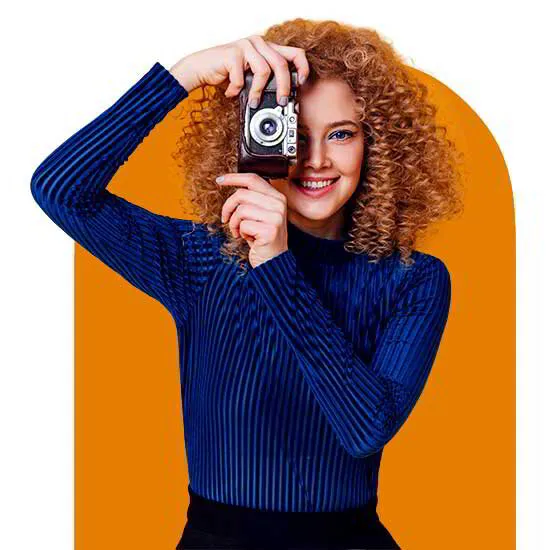 With her curly hair framing her determined expression, a photographer confidently holds her camera, capturing moments and preserving memories through her lens
