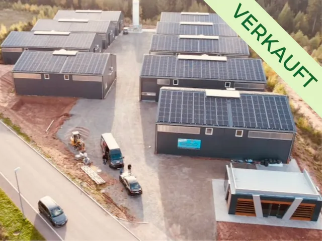 Luftaufnahme eines Gewerbeparks mit mehreren Gebäuden, deren Dächer mit Solarpanelen bedeckt sind. Diese Anlage ist bereits verkauft.