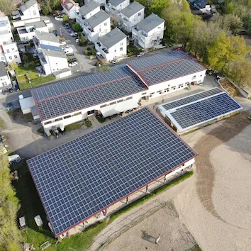 Luftaufnahme von Gebäuden mit Dächern vollständig bedeckt mit Photovoltaik-Panelen