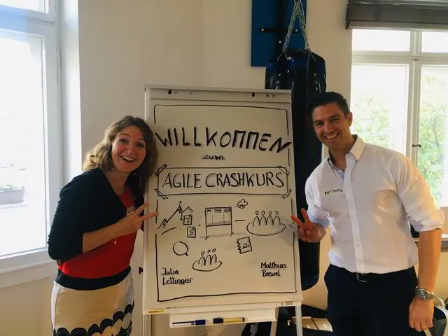 A smiling woman and a men standing next to a flipchart for an agile working crashkurs