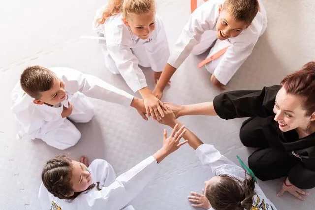 Mitarbeiter und Kinder legen die Hände motivieren für einen Motivationsruf im Kreis aufeinander