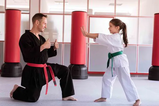 Karate Trainer von Karte Geiger dein ein Kind für seine Selbstverteidigungstechnik lobt