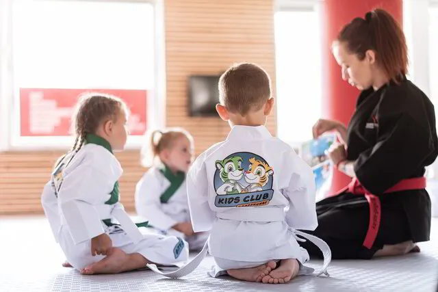 Kinder Karate Kids die zusammen mit ihrer Trainerin im Gesprächskreis über wichtige Alltagsthemen sprechen, hier geht es um den Umgang mit Fremden, alle hören aufmerksam zu