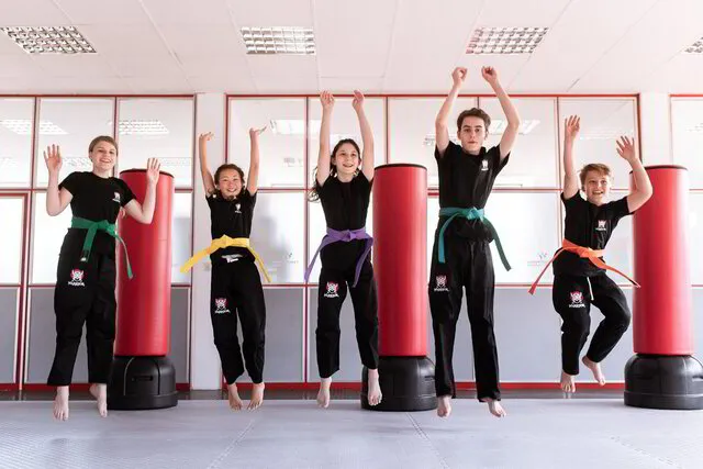 5 Karate Teenager über voller Freude Strecksprünge an ihrem Standort in der Nähe ihres Wohnortes, gemeinsames Training im Dojo