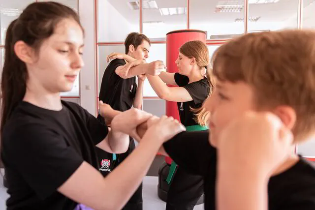 Jugendliche üben zusammen Selbstverteidigungstechniken in der Warrior Karate 10-15 Jahre Einheit