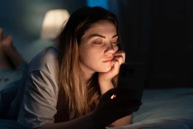 Young girl using a cell phone while lying in bed