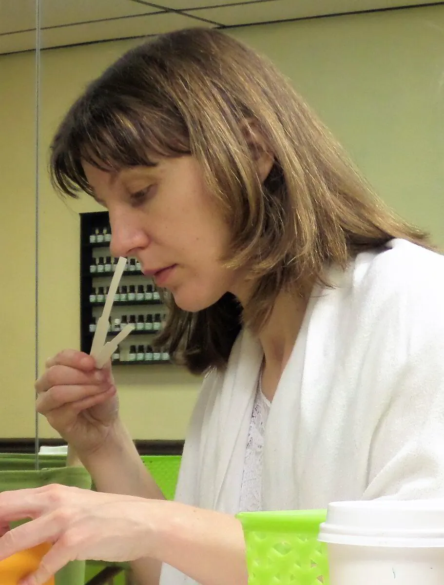 Woman in a lab coat smelling essential oils pipette