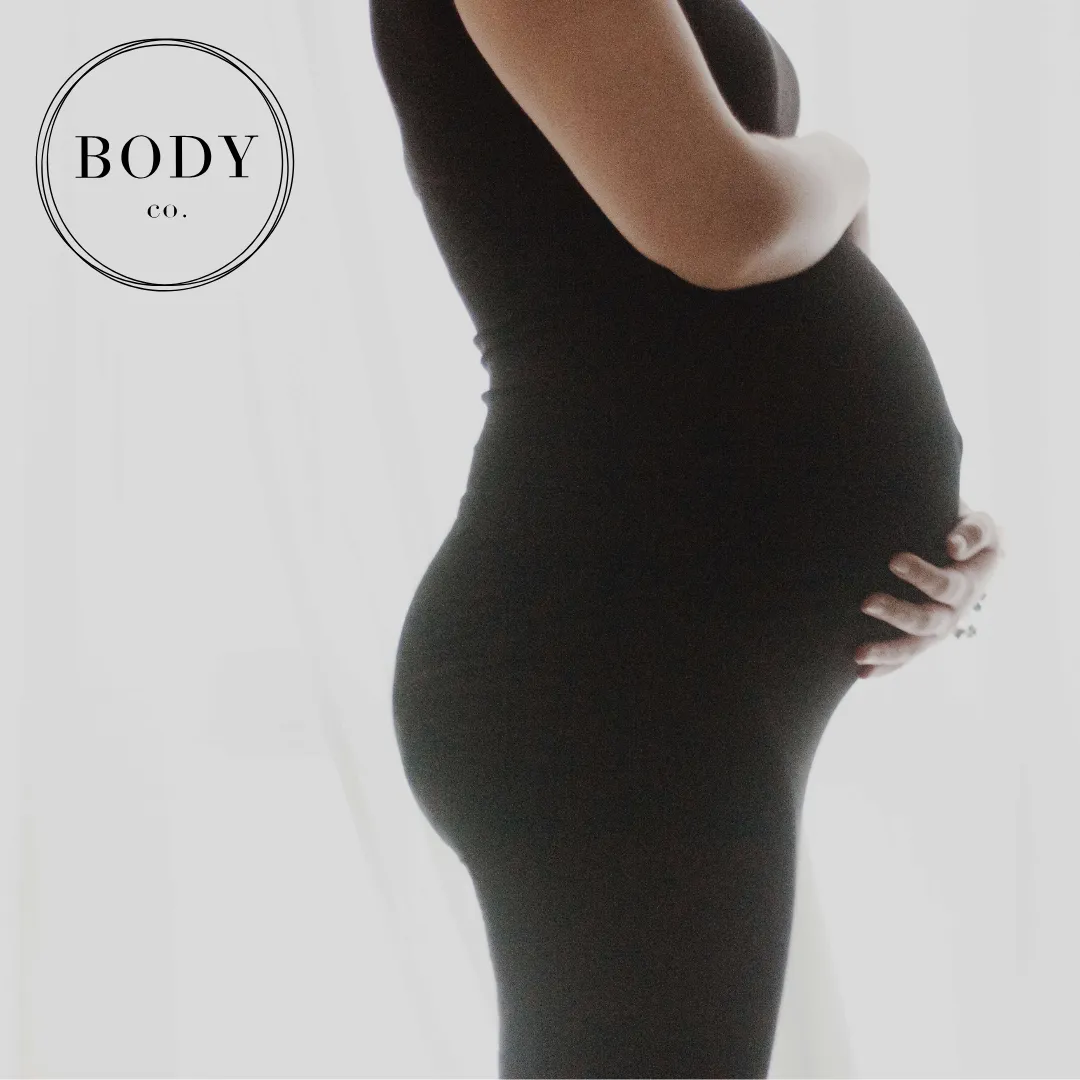 pregnant woman in black dress holding belly