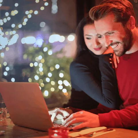 Un homme heureux et détendu travaille sur son ordinateur avec son épouse à son côté.