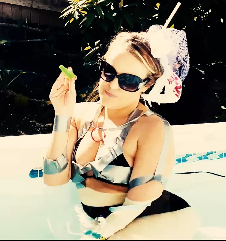 Still shot from Abby London's 'Anxiety' music video featuring the political anti-pop singer in a pool, creatively adorned in a bathing suit made of recycled trash