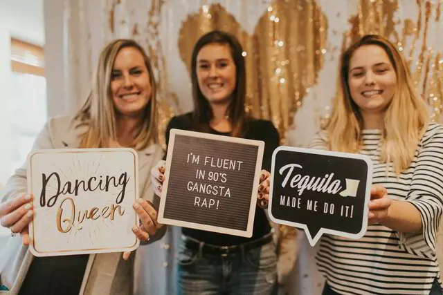 three ladies posing with photo booth signs